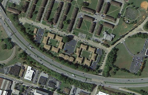Aerial photo showing community for which a noise barrier was proposed by TDOT, Project TDOT-3. It shows apartments with shared common areas. The barrier was determined to be reasonable due to unanimous support for the barrier. The roadway curves from the upper left to lower right corners. The residential land uses are above the road and commerical land uses below the road. 
