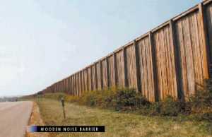 photo:  wooden noise barrier, viewed from the highway side with vegetation in front of the barrier (photo is intended to illustrate a typical example of a well-designed and well-constructed wooden noise barrier)