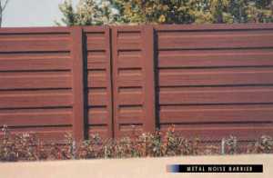 photo:  metal panel noise barrier, viewed from the highway side with vegetation in front of the barrier (photo is intended to illustrate a typical example of a well-designed and well-constructed metal noise barrier)