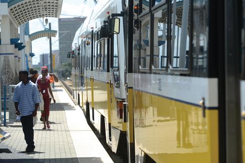 Photo of a commuter train at a station with people on the platform.