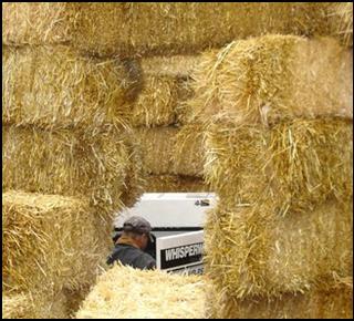 Low cost straw bales are stacked like blocks in a four-sided enclosure. One corner is open so a worker may access the equipment. The access site can be blocked when worker is completed with task. 