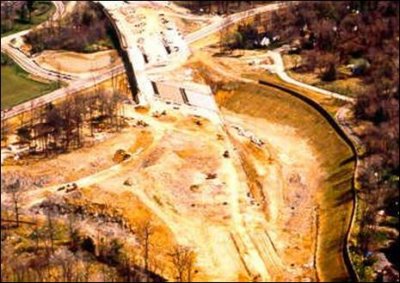 An aerial photo of a new highway on new location construction site where a noise berm/wall combination has been built before the initial grading activity 