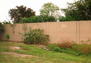 Photo of a noise barrier showing the importance of placing vegetation so that it does not block aesthetic features. In this example, a shrub blocks an icon panel. 