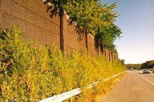 Photo of a concrete noise barrier with a brick texture surface treatment