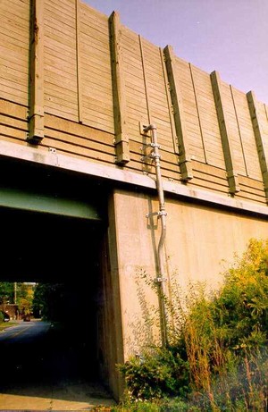 Photo of a bridge-mounted noise barrier with a waterline connected to the back of the barrier and extended to accommodate firehose connections