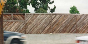 Photo showing a wooden noise barrier with the slats at an angle to create an interesting surface pattern