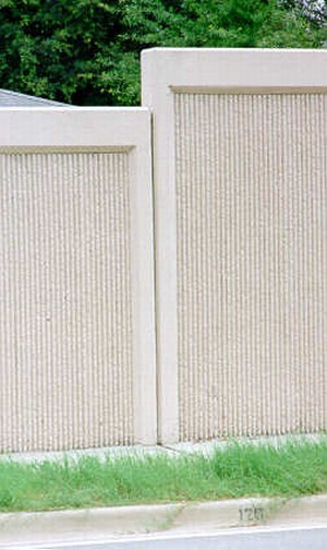 Photo of a concrete noise barrier with a vertical grooved texture surface treatment