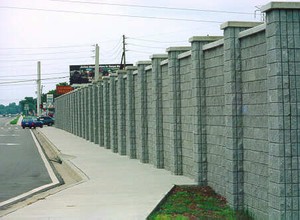 Photo of the roadway side of a noise barrier with a stone texture on a city street 