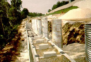 Photo of noise wall caisson foundations behind pre-manufactured retaining wall