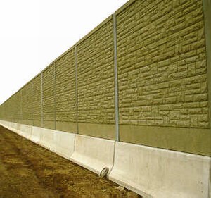 Photo of a pre-cast concrete noise barrier with a form-lined brick surface texture mounted on top of a smooth concretesafety barrier