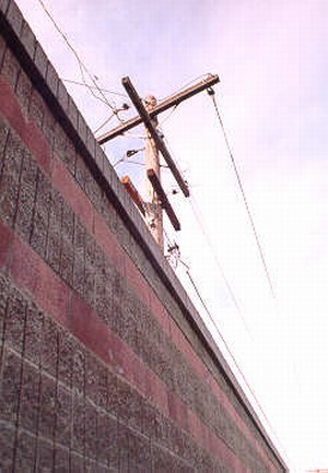 Photo showing the top of a noise barrier and overhead power lines.