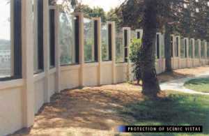 photo:  noise barrier, with transparent panels set between posts on short non-transparent panels, viewed from the residents= side of the barrier (photo is intended to illustrate a typical example of designing a noise barrier to protect residents= views of scenic vistas)