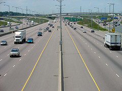 Loud or annoying, unwanted sound is noise. A photograph of a multi-lane roadway with travel in both directions is emanating sound waves to the photograph of a human ear.