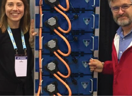 Image shows a man and a woman standing next to a lithium ion battery bank.