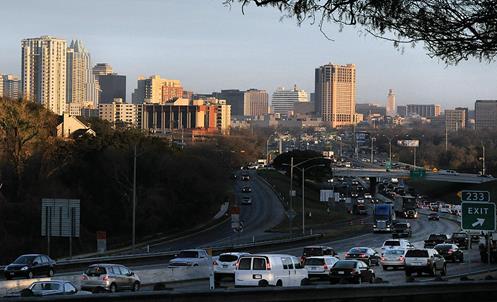 Photo of a divided highway with heavy traffic near a city