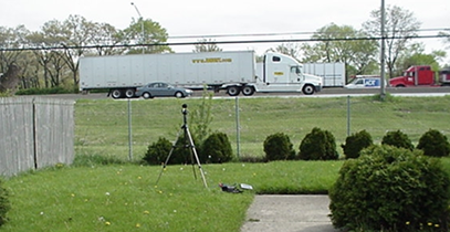 Noise measurement near a roadway on a hill with a heavy truck passing by.
