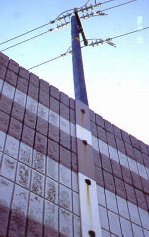 Photo showing the top of a noise barrier and overhead power lines.