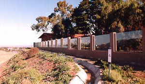 Photo showing a concrete drainage channel in front of the noise barrier