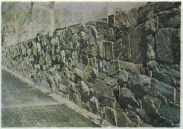 A coarse textured stone wall.