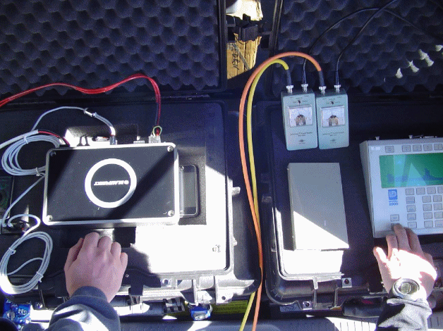 This figure contains 2 photographs on the EFR instrumentation.  The first illustrates two microphones a set distance away at two different heights above the travel lane and a point source in the form of a compression driver tube.   The second illustrates the tone generator and electronic equipment used to record that data. 