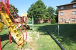 Title: A playground area at an apartment complex - Description: A portion of a playground area near three-story apartment buildings.