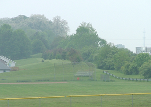 Title: Earth Berm - Description: A residence near a playing field being shielded by a berm.