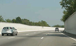 Title: Roadway with Parallel Barriers - Description: Parallel noise barriers at the edge of pavement of a roadway shown with two automobiles.