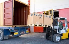 Forklift moving boxes into the back of a truck.
