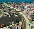 A highway running between a series of buildings and a waterway outlet. 