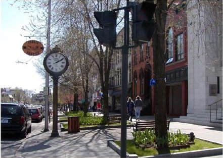 Photo: a sidewalk with trees, a Walk sign, and a clock.