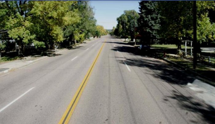 Photo of a treelined 4 lane undivided highway. Complete