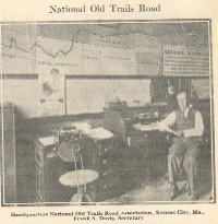 Frank Davis, who served the National Old Trails Road Association for many years, is shown in the Association's headquarters in front of a map of the trail.