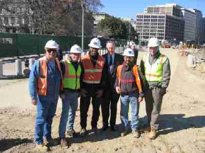 Former President George H. W. Bush visited the Pennsylvania Avenue construction zone in March 2004.  This photo was taken on Pennsylvania Avenue next to the west entrance to the White House.  From left to right:  Chris Dupont (consultant inspector), John Roddy (Project Manager for Lane Construction Company), Mike Tyree (FHWA), former President Bush, Jorge Alvarez (FHWA Project Engineer) and Gerald Rench (consultant inspector).  (Photo courtesy Eastern Federal Lands Highway Division.)