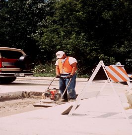 Figure 12 photo of vibratory plate compactor being used to prepare the area for patching