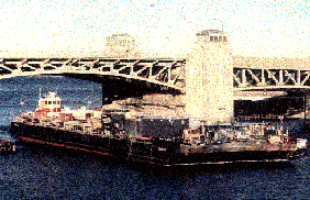photo of a barge going under a bridge
