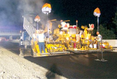 Photo of a road crew laying asphalt at night.