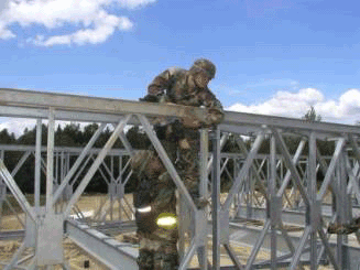 A photo showing a Bailey Bridge assembled with a U.S. soldier inspecting the bridge.