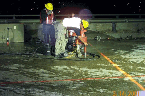 Picture showing the drilling and the installation of the lifting cables prior to saw cutting and removal of existing sections of the James River bridge deck.
