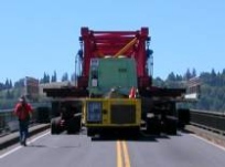 SPMTs transporting new deck panel from fabrication site adjacent to bridge.