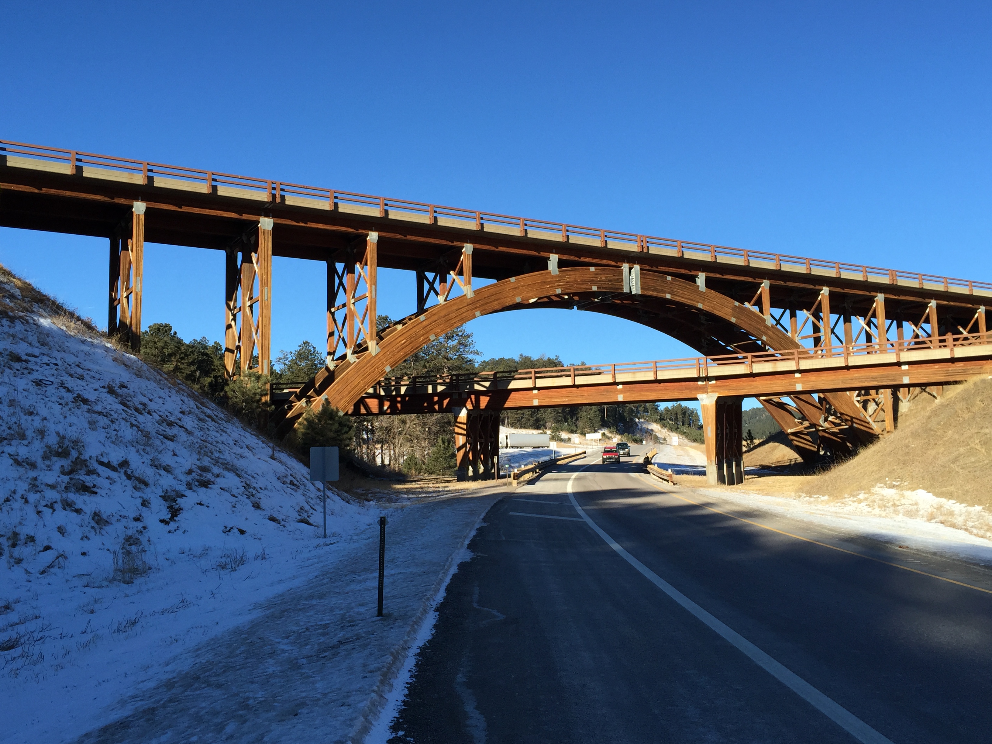 The image depicts a timber bridge in the Black Hills National Forest.