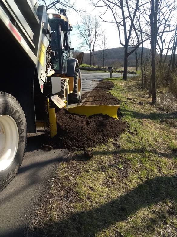 Sidewinder innovation spreading dirt along the side of a roadway.