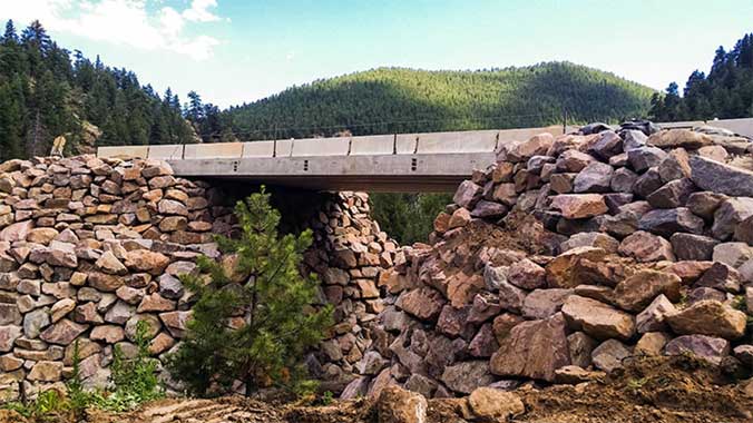 View of completed bridge with a near-vertical rockery used to build a bridge embankment in a stream.