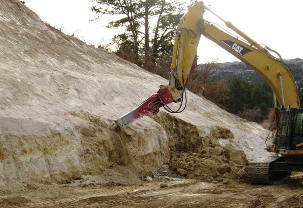 Photo. A hydraulic hammer expanding a sculpted area, creating planting areas and more natural-looking slope variation.
