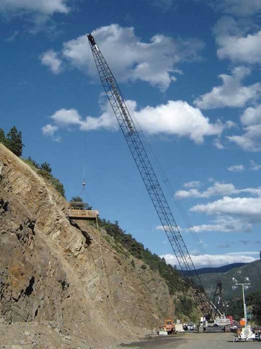 Figure 47. Photo. Installing rock reinforcement using a drill rig suspended from a crane.