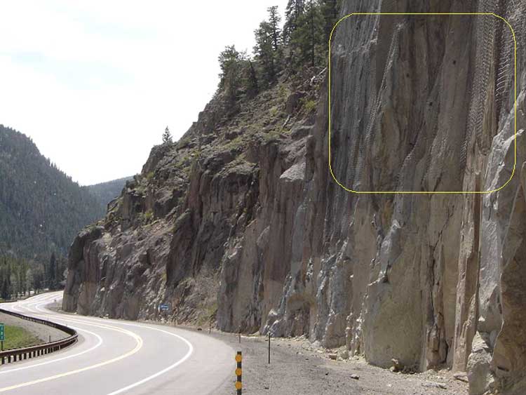 Figure 60. Photo. Rock slope treated with colored draped rockfall mesh.