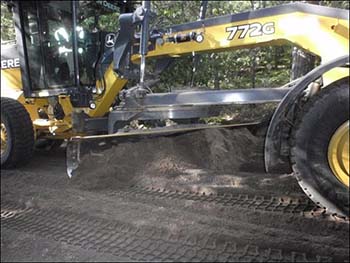 Grader flattening the ash/soil mixture.