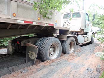 Wheels of a big truck sinking into the soft road.