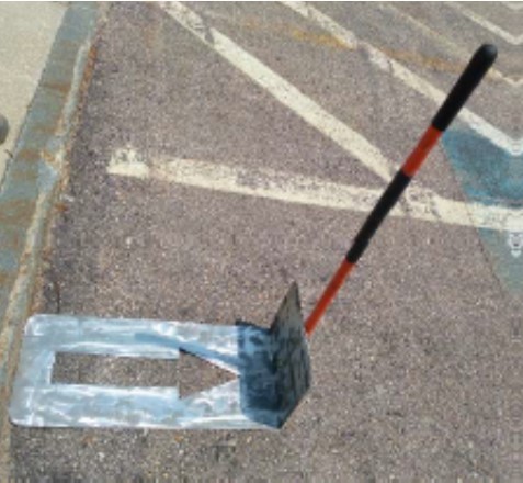 A metal device with arrow shaped cut-out and handle on the street
