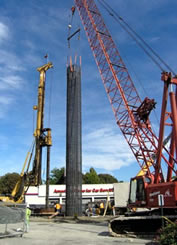 Photograph of the placement of a steel reinforcement cage into a drilled shaft for foundation construction.