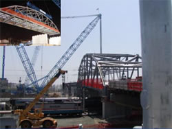 Photograph of the placement of a bridge span using high capacity cranes.